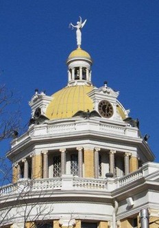 The Goddess of Justice soars above the city of Marshall.  The clock faces and eagles are also clearly visible.