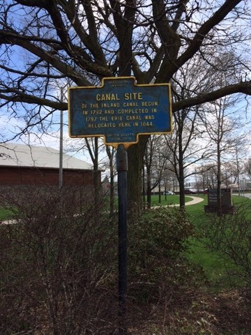 As the marker appears in 2018 looking east toward Black River Blvd, or past the Willett Center and toward the entrance to the Fort.  The intersection of Erie Blvd. and James St. is at your back from this angle.