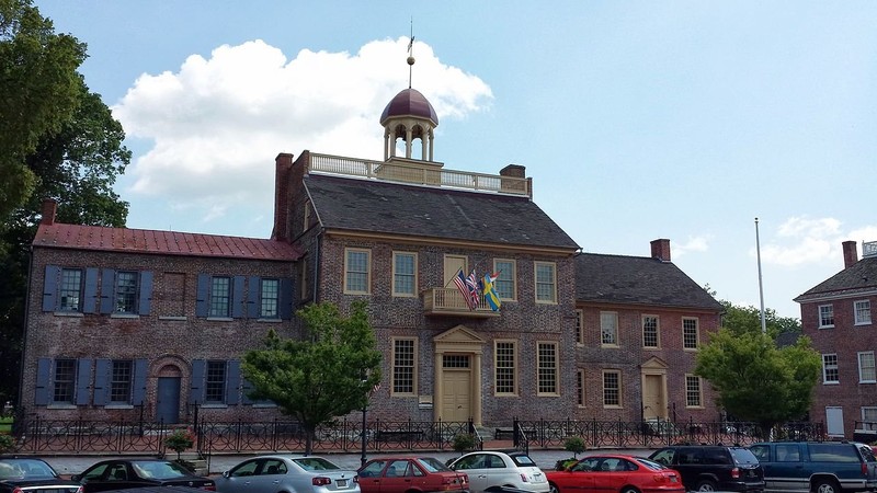 Large brick building in three distinct sections. The middle is the largest and has a domed cupola on the roof. 