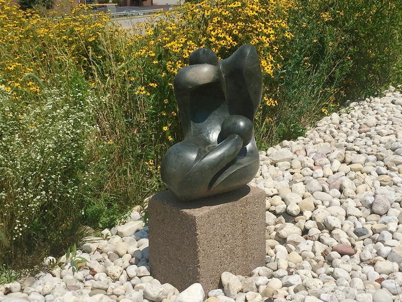 Laxon Karisi's "Human Suffering." The sculpture is made of serpentine, a type of rock with a naturally rough, greenish appearance, similar to a snake.