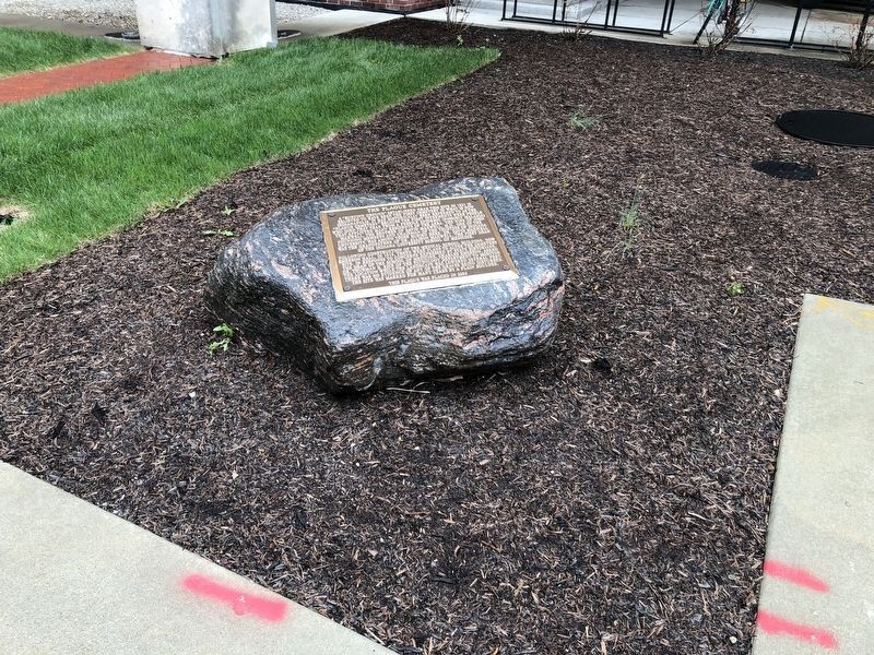 Photograph of the Plague Cemetery historical marker on its boulder base.