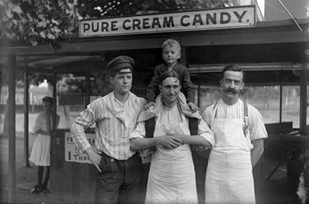 Humphrey family and friends standing for a photo op in front of a Pure Cream Candy stand at the park.