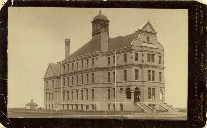 four-story brick building with cupola on top.