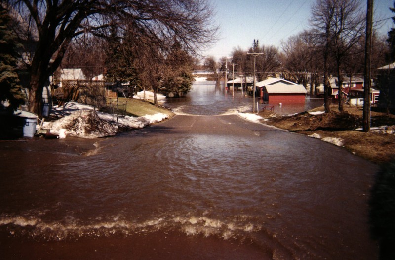 Flood waters fill streets and rise halfway up walls of houses.