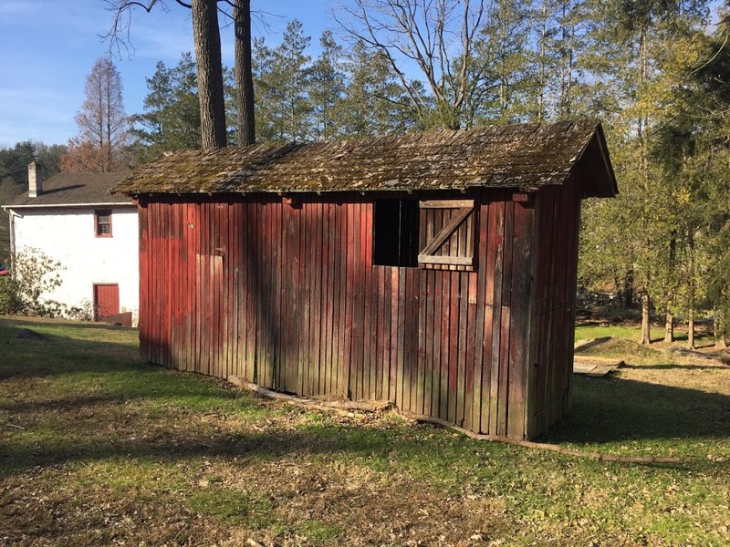 Image of a narrow structure made of spaced wooden slats, painted red.