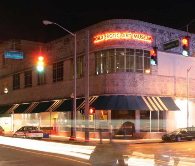 A rounded facade on the corner of a street with a lit sign reading "World Erotic Art Museum"