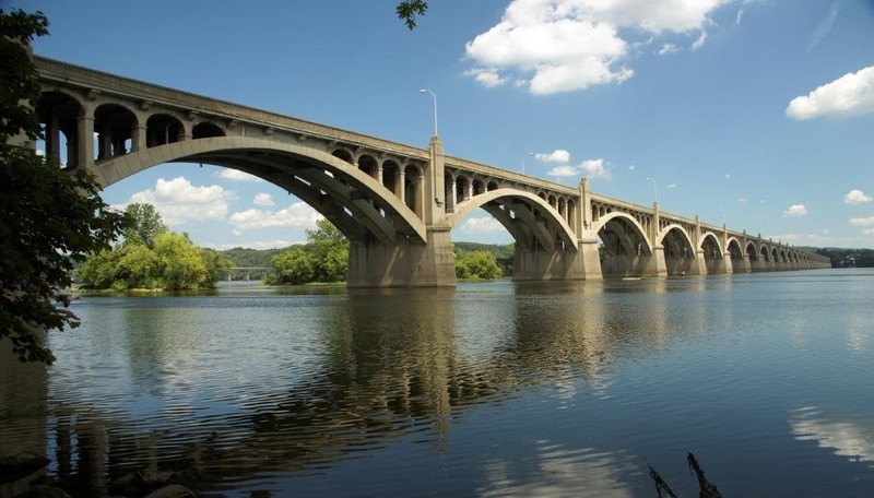 Erected in 1897, the current bridge measures 7,374 feet in length earning the title of the longest concrete arch bridge in the world. A physical and cultural staple of the region, the bridge is listed on the National Register of Historic Places.