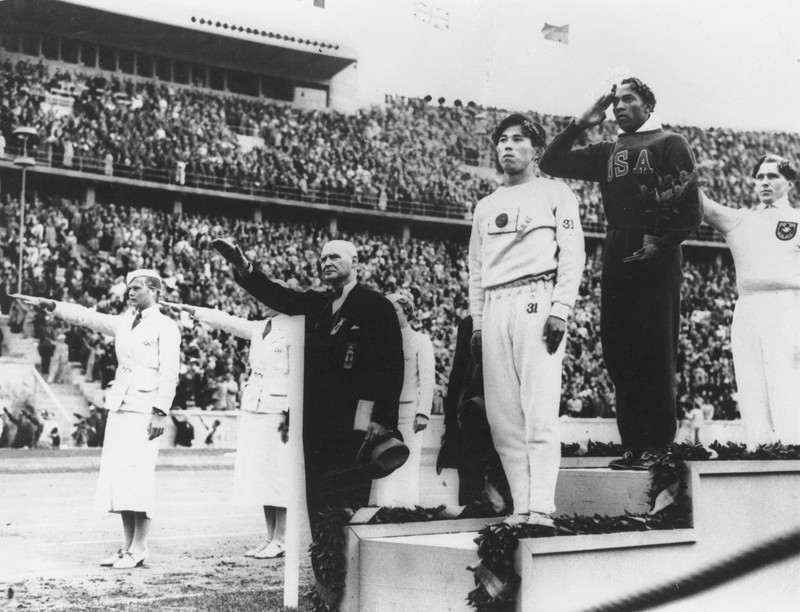 1. Jesse standing victorious while the National Anthem of the United States is played after winning gold. (Encyclopaedia Britannica).