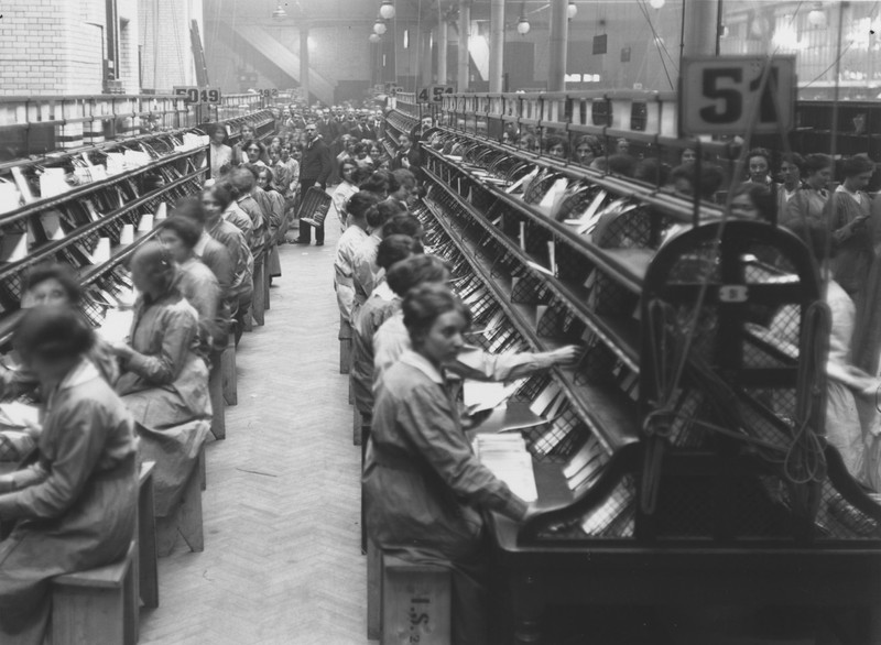 An image dozens of women working in the Post office to keep the United States of America functioning during WW1. 