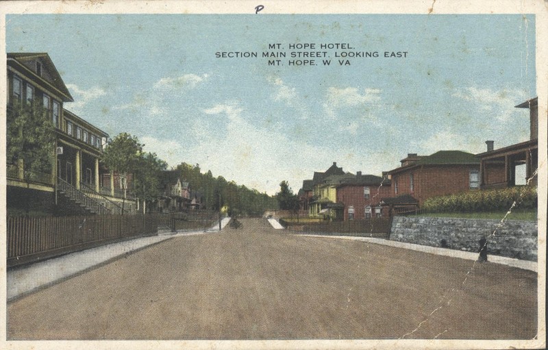 Post card of street view of the former Mount Hope Hotel (left) now known as the Mountainair Hotel.  Notice how the porch is elevated away from Main St.