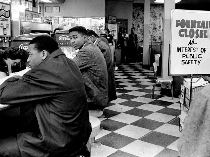 The student protesters sit at the Walgreens counter in protest of the sign. 