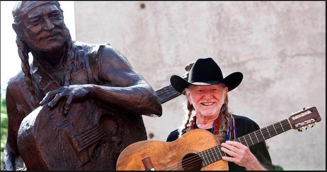 Willie Nelson posing with his well known guitar " Trigger" beside of his statue in Austin, Texas. 