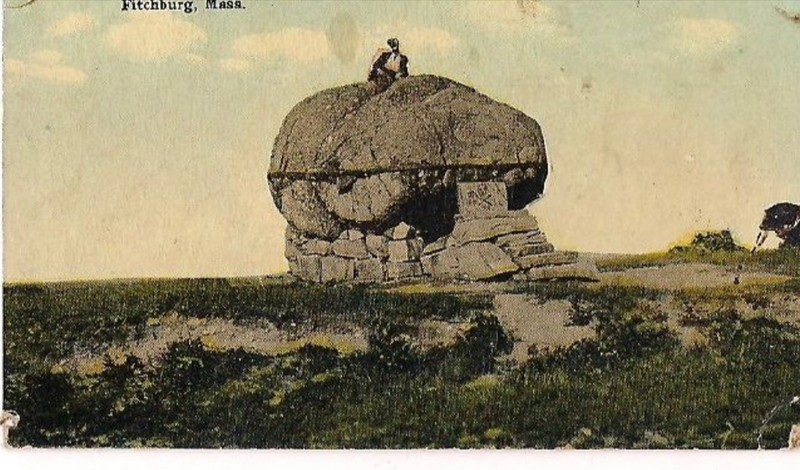 A colorful photographic postcard that features the Rollstone Boulder on top of Rollstone Hill. The photo features the iron band that was used to keep the boulder in place. 