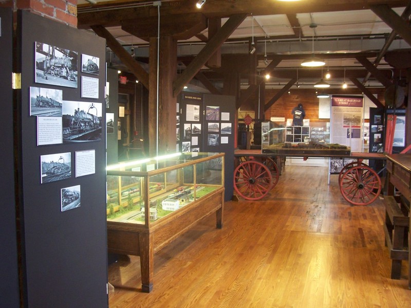 A view of museum exhibits with railroad machinery, cabinets with objects, and exposed Mill architecture.