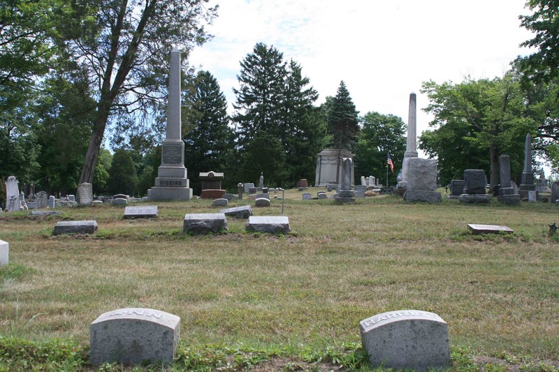 two simple stone grave markers with several larger stone grave markers in the background.