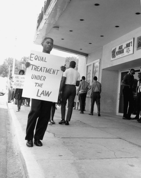 A man holds a sign outside of the theatre during the protest.