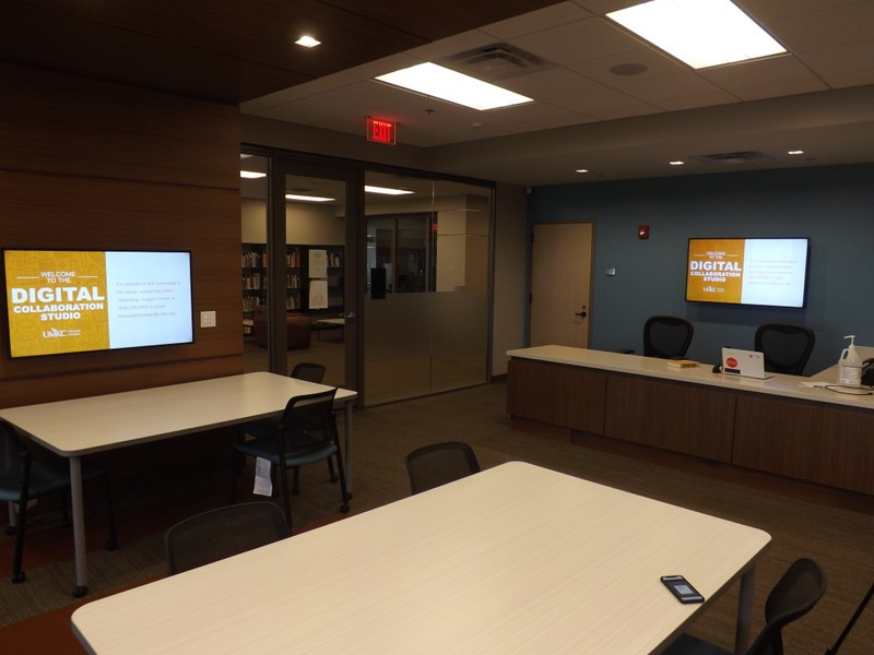 The center of the room includes tables centered around high-definition monitors to support collaboration.