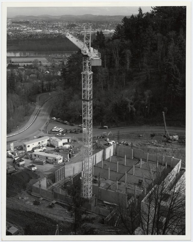 Black and white photograph of the Casey Eye Institute construction site with crane in foreground, with Portland waterfront visible in background.