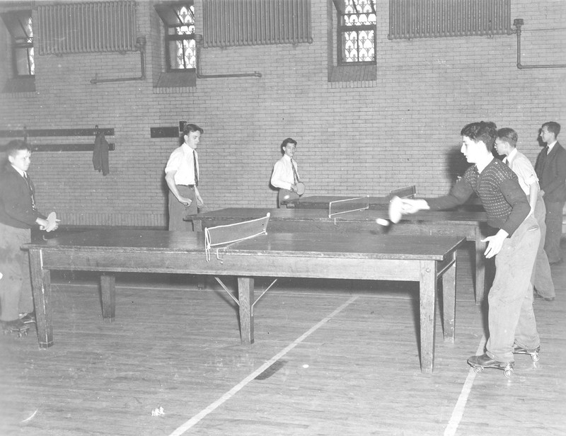 1939 photo of quarantined students playing ping-pong on roller skates in the Armory during scarlet fever epidemic.