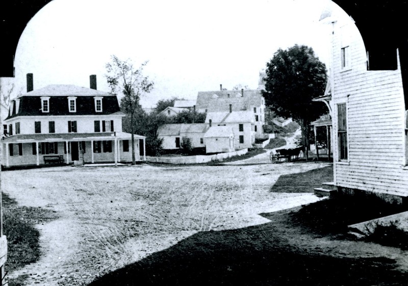 Seen here through the covered highway bridge (which was replaced with the stone highway bridge in 1935), is the Old Central House, a boarding house where a group of Irishmen who helped build Contoocook’s railroads boarded.  Today it is the site of Mr. Mike’s gas station.  