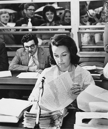 At the pivotal June 27 meeting, Alice Moore reviews transcripts as protesters watch through the board office auditorium windows. She originally ran on the platform that sex education should not be taught in schools.