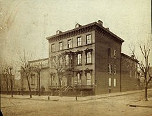 Italianate mansion photographed from across street intersection, with leafless trees.