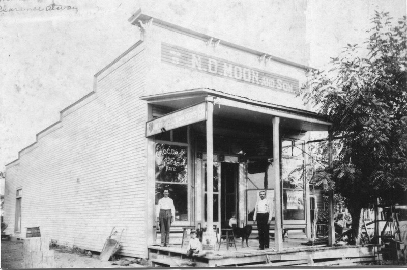 A black and white photo of a building with people standing in front of it. 