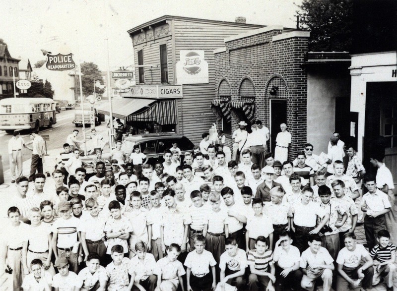 This is a photo from 1949 showing a group of children wait to be picked up for a Yankee’s game for a sponsored night out by the Highland Park Police Department, which was located in the 1-story brick building in the center. In 2018-19, this Alexander Merc