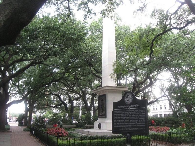The monument in Savannah Georgia is surrounded by other monuments and massive trees.