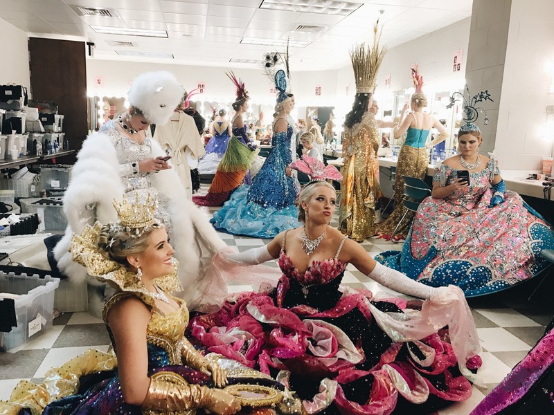 This image depicts a "behind the scenes" view of the ladies waiting to be escorted across for the audience to see.