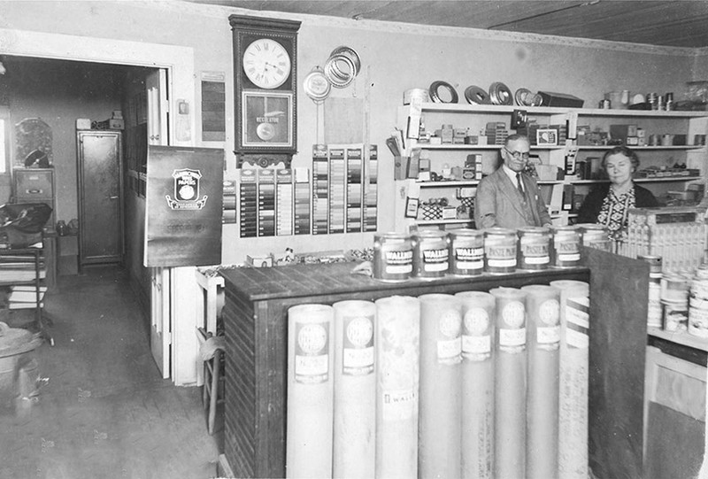 A black and white photo of a man and woman working inside a store.