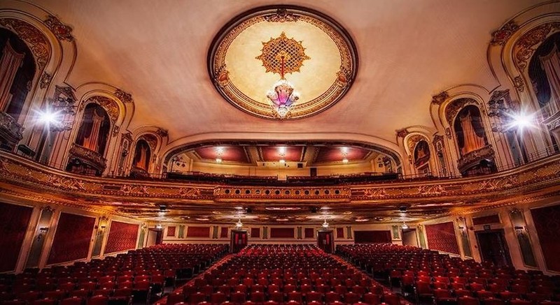 A picture of the concert hall including its grand chandelier and seating.