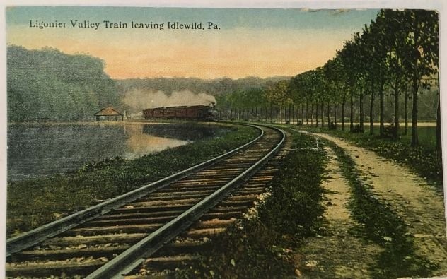 A postcard depicting the Ligonier Valley Rail Road’s train/train tracks leaving the Park. Idlewild’s presence helped turn the Ligonier Valley RR from being a purely coal transport into a vessel for passenger travel.

"LHHC"