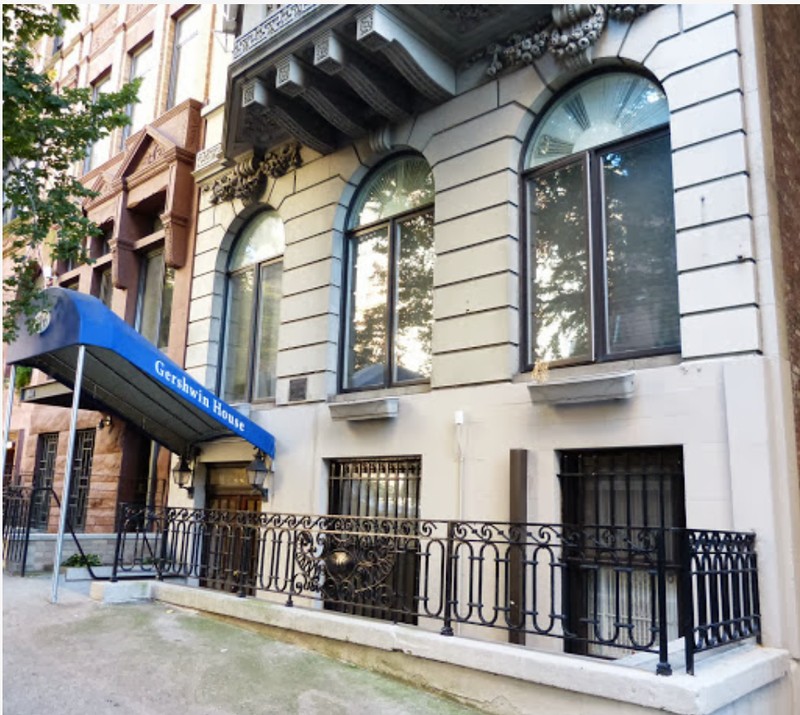 The original doorway at parlor level is now a window and an awkwardly-angled marquee leads to the entrance below street level -- photo by Alice Lum