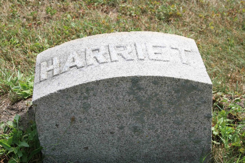 A simple stone marker with a curved top and the name "Harriet" in raised letters on the top.