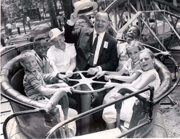 Six children and an adult enjoying a ride at the park (black and white) 