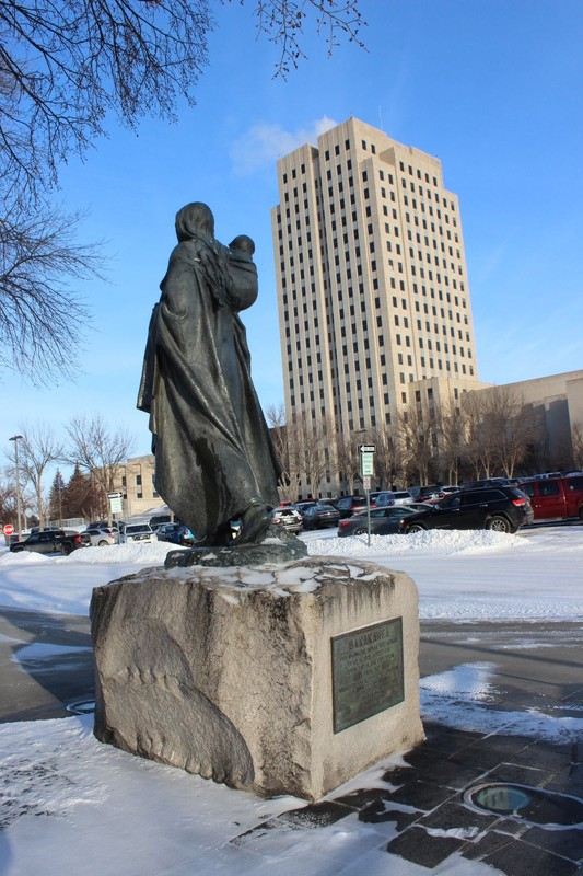 Reverse of Sakakawea statue with North Dakota capitol in background