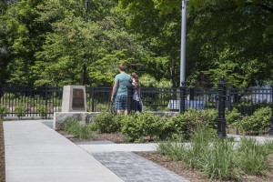 A couple enjoying the park on a beautiful day. They are stopped admiring the plaque dedicated to Edith Ammon and her fellow ladies that helped save the Block House.