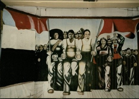 A mural that once covered an interior wall at Casa Aztlan, painted by Marcos Raya and depicting community members marching under the red flag of the Huelga (strike) (Credits: Dr. Margaret LaWare, 1991)