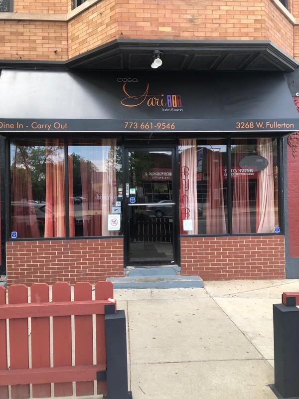 The front entrance of Casa Yari at 3268 W Fullerton Avenue, Chicago, IL 60647. The vibrant red entry invites customers in for dine in or carry out options. Noted on the windows is the BYOB option for the restaurant.