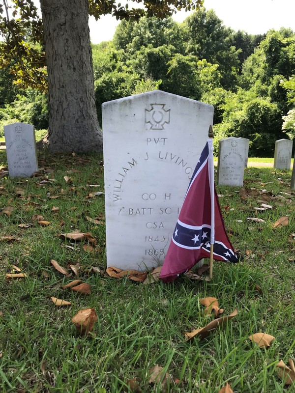 A gravestone decorated with a Stars and Bars flag. 