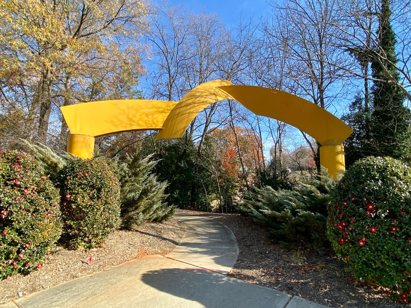 Yellow metal sculpture  over a greenway trail