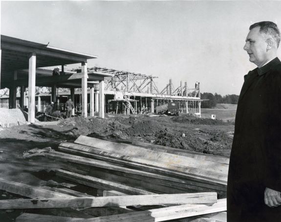 Black and white image of a man looking at a building that is under construction.