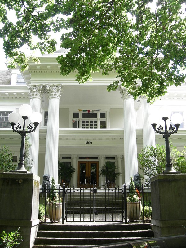 A frontal view of the estate highlighting its grand white columns and entryway. The original architect, Frederick Sexton, was known for creating lavish residences: much of what attracted George Parker to buy the home.