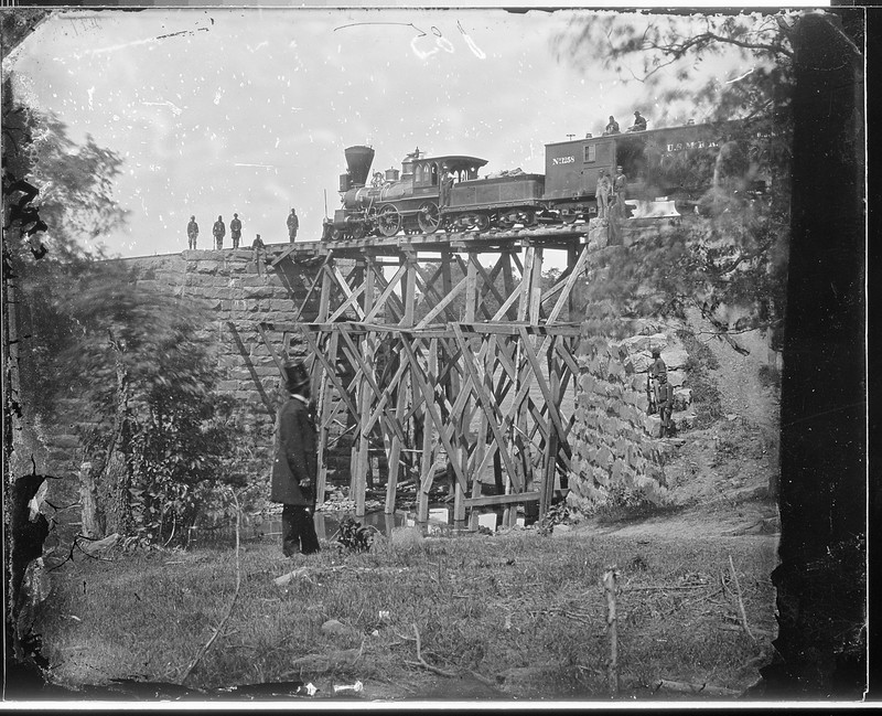 This picture is widely reported as being of the original Accotink Bridge, and it is included on several markers. However, other sources dispute the claim. The picture, taken by Matthew Brady or one of his associates, is simply labeled "Cars of U.S. Military R. R., and bridge built by Soldiers. Orange and Alexandria R. R." by the National Archives.