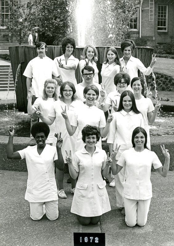 Photograph of the Radiology Class of 1972, in front of the campus fountain. Those pictured are raising their hands in peace signs, along with one person raising a fist - generally a sign relating to the black power movement.