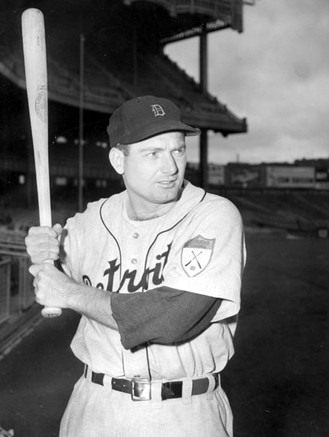 A black and white photo of a man in uniform with a bat in his hands.