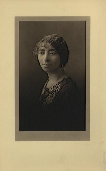 Young woman, short wavy bob wearing a dark dress with an embroidered flower bodice