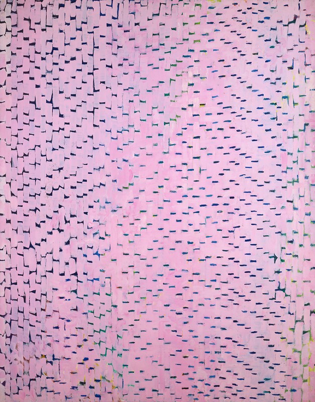 Image of Alma Thomas' 1973 acrylic-on-canvas painting entitled "Cherry Blossom Symphony." Created using her signature style of short, bold brushstrokes, this one overwhelmingly in shades of light pink, over a darker background of blues that can be seen through the brushstrokes.