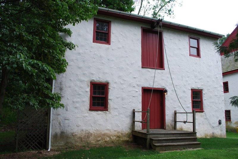 Image of 2-story stuccoed building with a pulley system above the central doors.